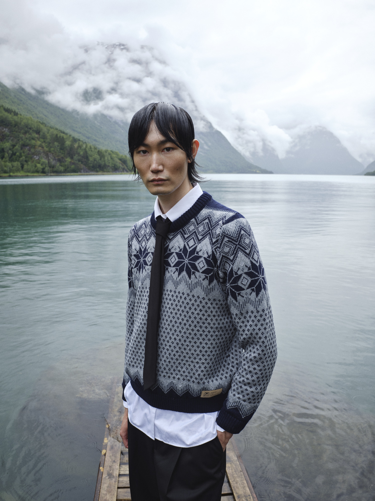 Female model wearing wool sweater standing by a Norwegian lake